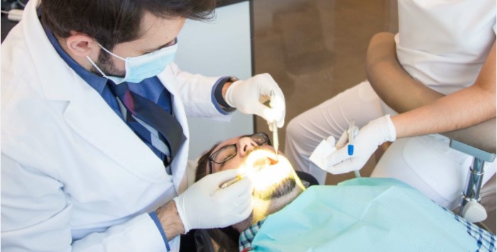 Dr. Rohi Atassi and his hygienist offering dental services to a pacient siting with his mouth open on a dental chair