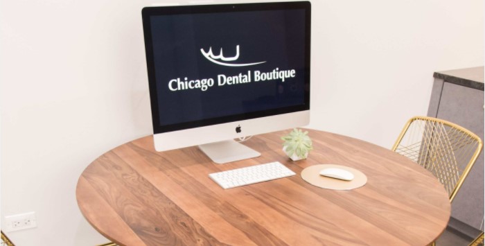 Table with a apple desktop on it showing the Chicago dental boutique logo